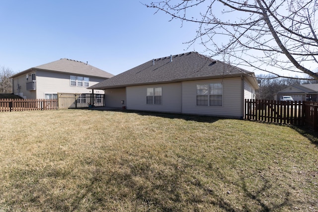 rear view of property with a lawn, a fenced backyard, and roof with shingles