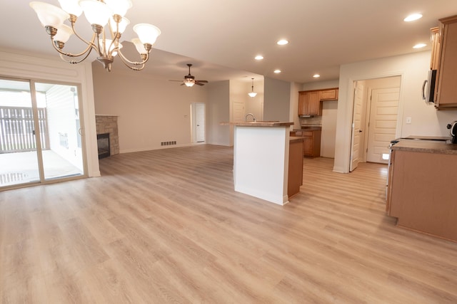 kitchen featuring stainless steel microwave, ceiling fan with notable chandelier, light wood finished floors, open floor plan, and recessed lighting