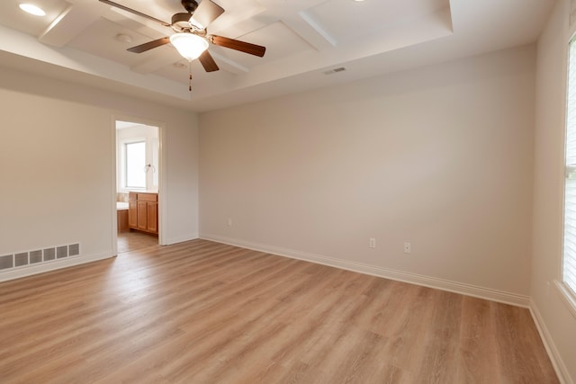 empty room featuring visible vents, plenty of natural light, light wood-style flooring, and coffered ceiling