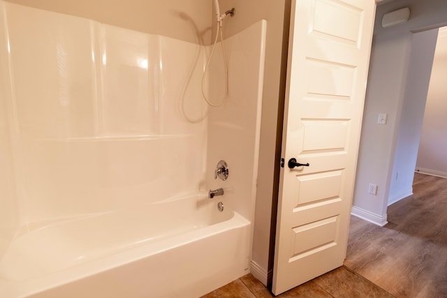 bathroom with baseboards, wood finished floors, and bathing tub / shower combination