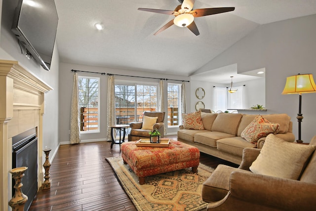 living area featuring dark wood-type flooring, baseboards, vaulted ceiling, a fireplace, and a ceiling fan