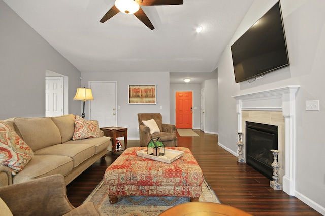 living area with baseboards, dark wood finished floors, lofted ceiling, ceiling fan, and a tile fireplace