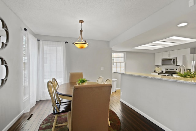 dining space with a wealth of natural light, visible vents, and dark wood-style flooring