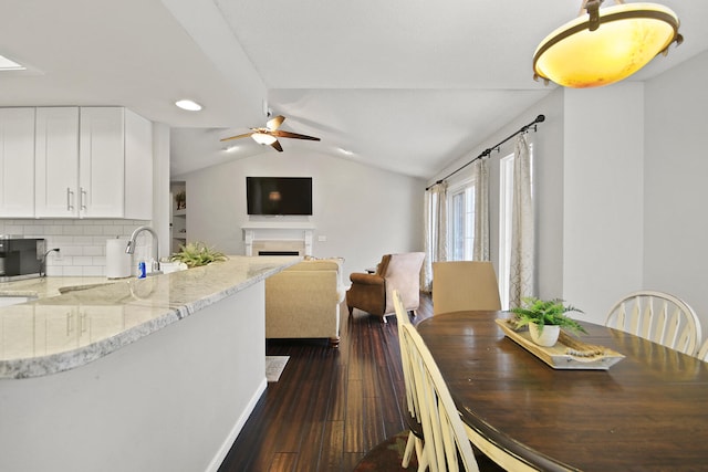 dining area with lofted ceiling, dark wood-type flooring, ceiling fan, and a fireplace