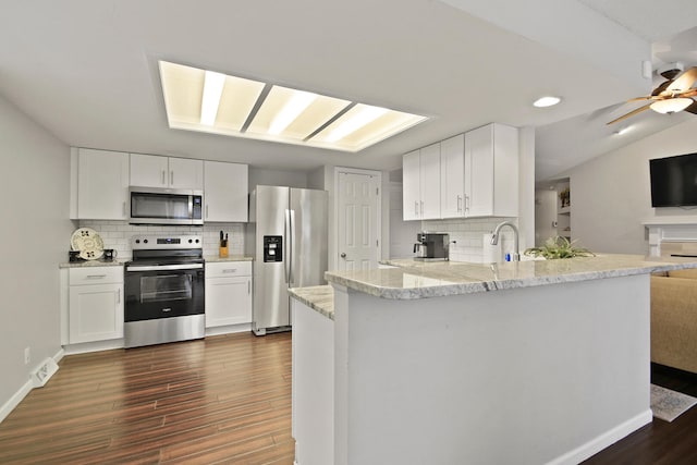 kitchen with stainless steel appliances, dark wood-type flooring, a peninsula, and white cabinets