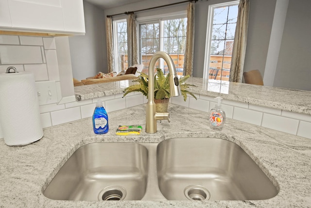 interior details featuring light stone counters, white cabinets, and a sink