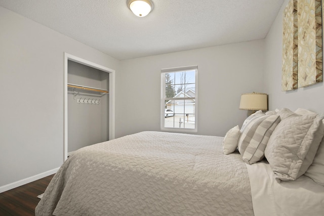 bedroom with a closet, baseboards, a textured ceiling, and wood finished floors