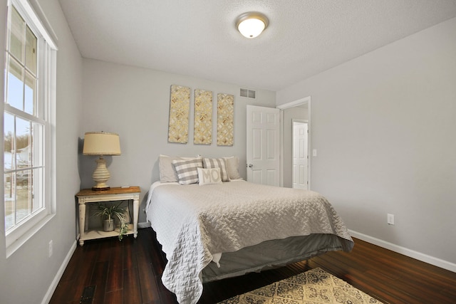 bedroom with visible vents, wood-type flooring, a textured ceiling, and baseboards