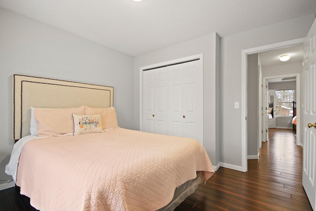 bedroom featuring dark wood-type flooring, baseboards, a closet, and a textured ceiling