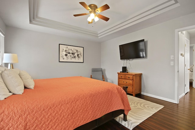 bedroom with a ceiling fan, a raised ceiling, wood finished floors, and baseboards