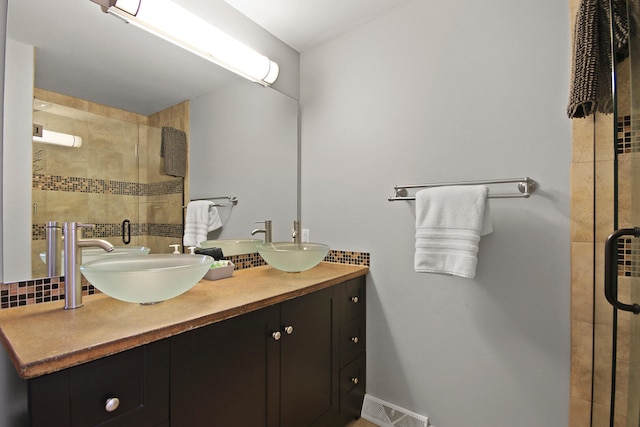 full bathroom featuring a sink, visible vents, a stall shower, and double vanity