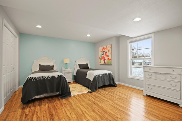 bedroom featuring a closet, recessed lighting, baseboards, and wood finished floors