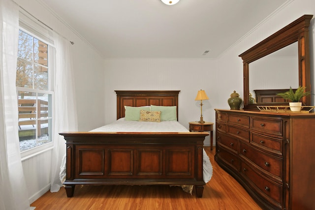 bedroom featuring multiple windows, ornamental molding, and wood finished floors