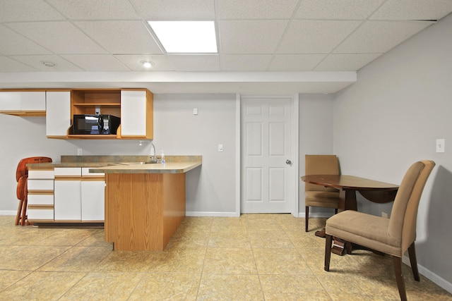 kitchen featuring white cabinetry, a peninsula, baseboards, and black microwave