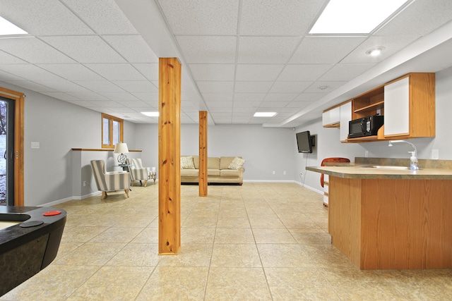 kitchen with a sink, open shelves, light tile patterned flooring, black microwave, and baseboards