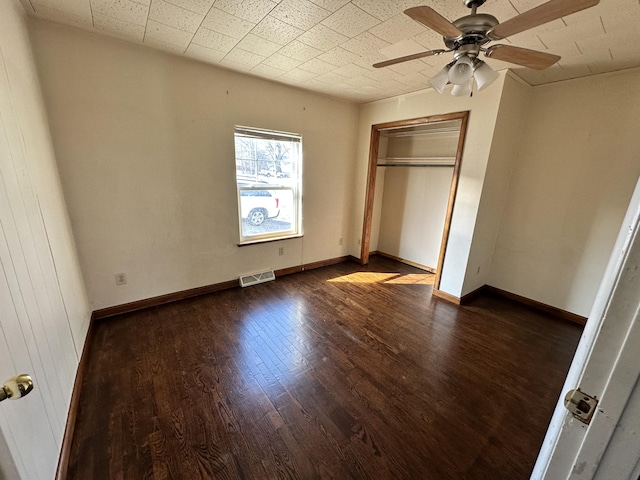 unfurnished bedroom featuring visible vents, ceiling fan, baseboards, dark wood finished floors, and a closet