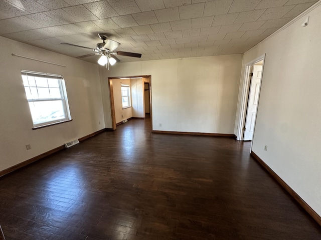 unfurnished room with dark wood finished floors, baseboards, visible vents, and ceiling fan