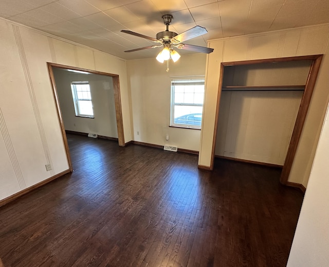 unfurnished bedroom with ceiling fan, dark wood-style floors, visible vents, and baseboards