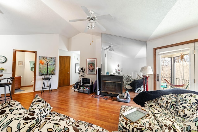 living area featuring lofted ceiling, light wood finished floors, and a textured ceiling