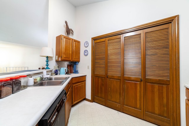 kitchen with dishwashing machine, light floors, a sink, light countertops, and brown cabinets