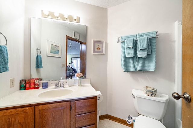 half bathroom with vanity, toilet, and baseboards