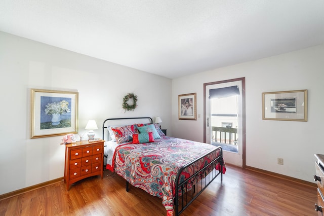 bedroom featuring access to outside, wood finished floors, and baseboards