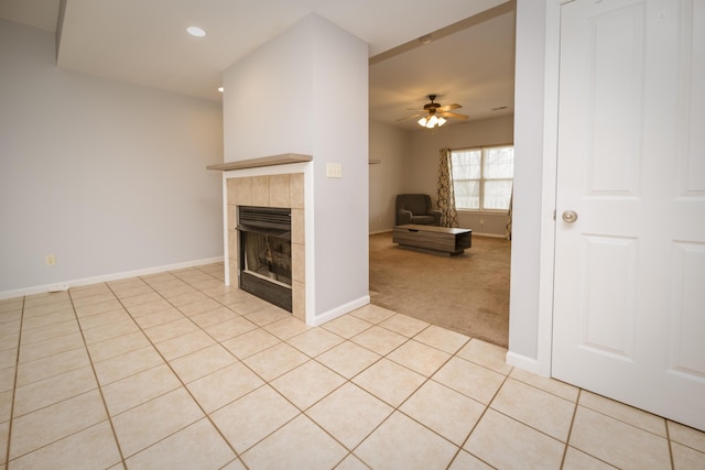 unfurnished living room featuring light tile patterned floors, a tiled fireplace, baseboards, and a ceiling fan