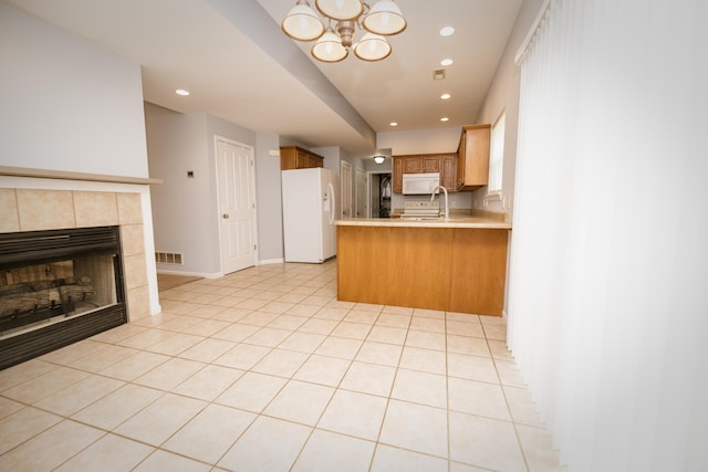 kitchen with visible vents, light countertops, a fireplace, a peninsula, and white appliances