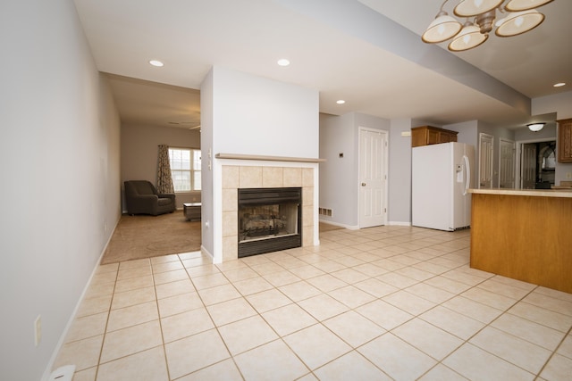 unfurnished living room with a tiled fireplace, light tile patterned floors, recessed lighting, and baseboards