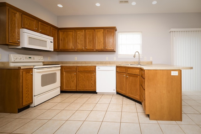 kitchen with white appliances, brown cabinetry, a peninsula, recessed lighting, and a sink