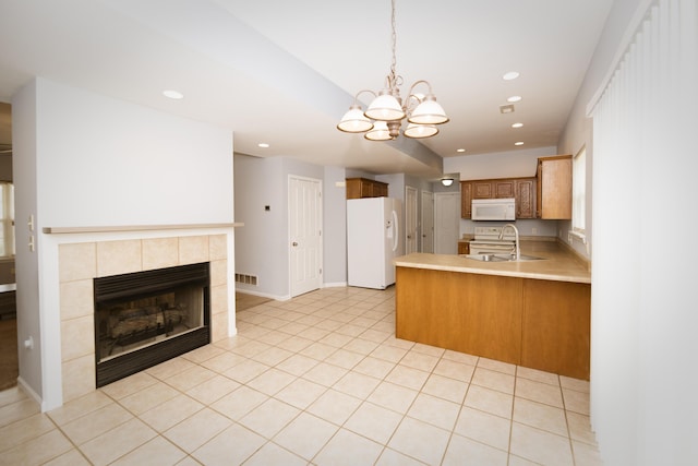 kitchen with visible vents, a sink, white appliances, a peninsula, and light countertops