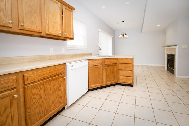 kitchen with a tiled fireplace, a sink, a peninsula, light tile patterned floors, and dishwasher