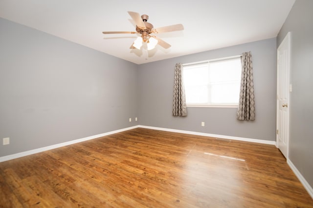 spare room with baseboards, wood finished floors, and a ceiling fan