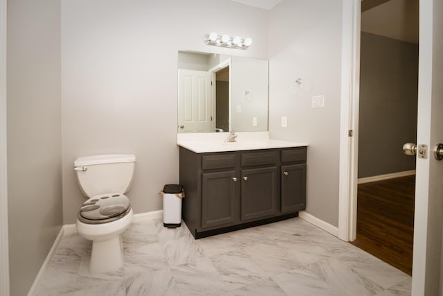 bathroom with marble finish floor, toilet, vanity, and baseboards