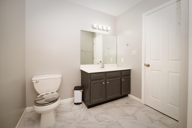 bathroom featuring marble finish floor, toilet, vanity, and baseboards