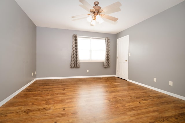 spare room featuring wood finished floors, baseboards, and ceiling fan