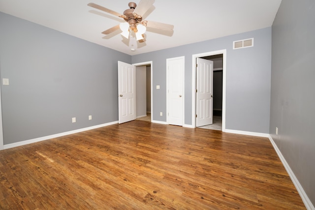 unfurnished bedroom with visible vents, a ceiling fan, baseboards, and wood finished floors