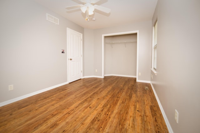 unfurnished bedroom with a ceiling fan, visible vents, wood finished floors, baseboards, and a closet