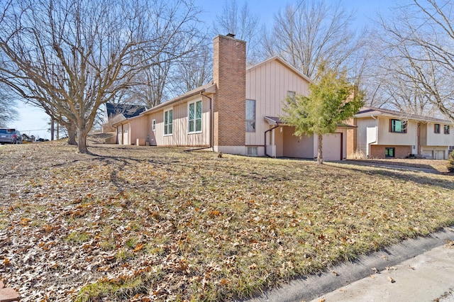 view of side of property featuring an attached garage and a chimney