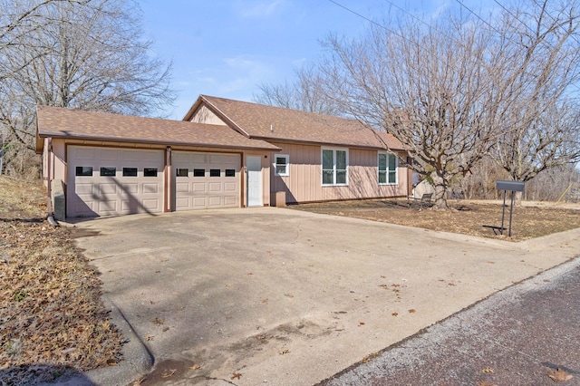 ranch-style house with a garage, roof with shingles, and concrete driveway