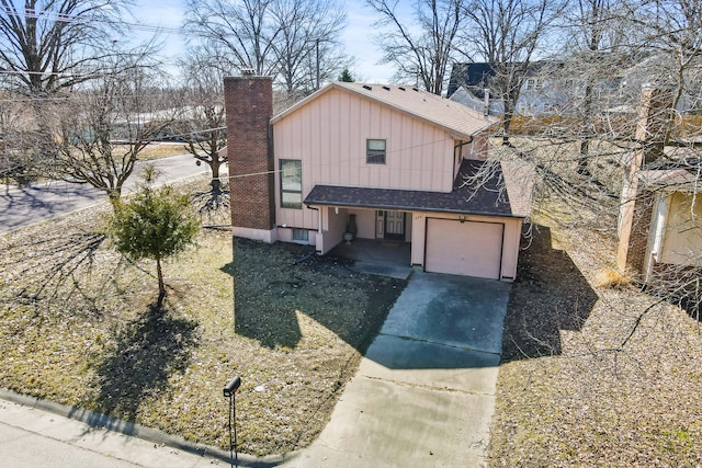 view of front facade featuring board and batten siding, a shingled roof, a chimney, a garage, and driveway