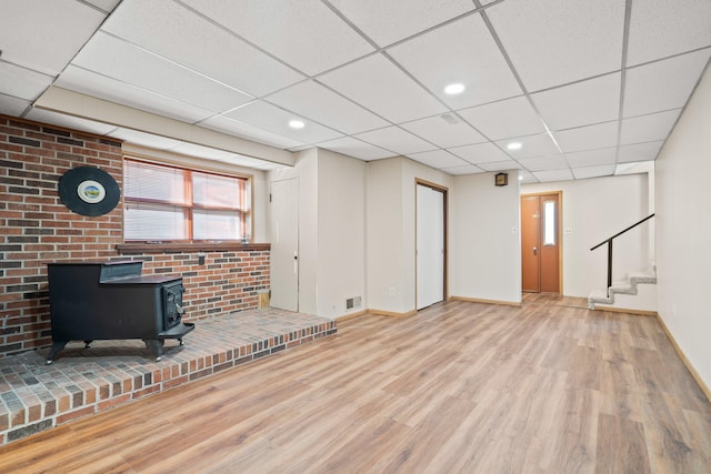 interior space with visible vents, a wood stove, wood finished floors, baseboards, and stairs