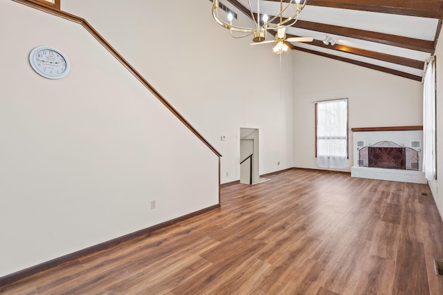 unfurnished living room featuring beam ceiling, high vaulted ceiling, wood finished floors, a fireplace, and a chandelier