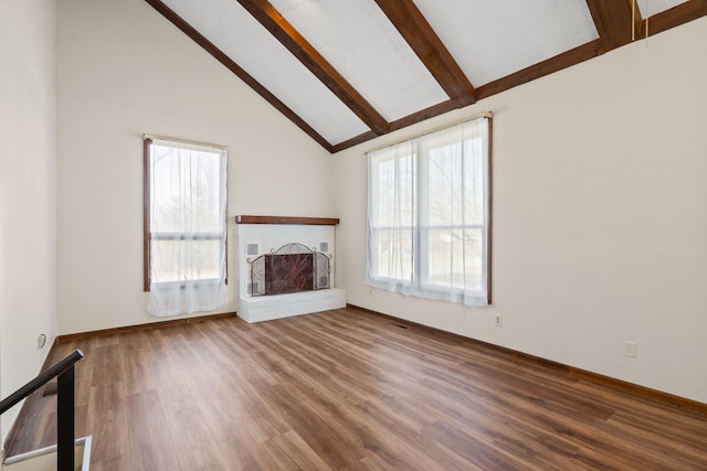 unfurnished living room with wood finished floors, beamed ceiling, a fireplace, and high vaulted ceiling