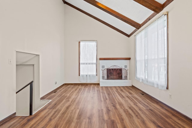 unfurnished living room with beamed ceiling, visible vents, high vaulted ceiling, wood finished floors, and a brick fireplace