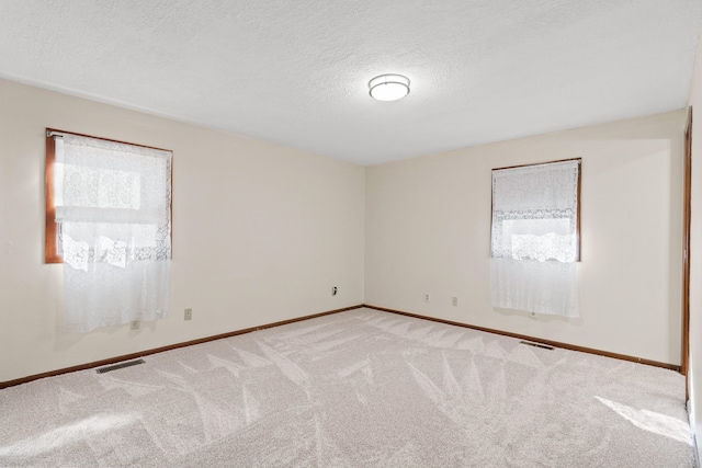 carpeted empty room with visible vents, baseboards, and a textured ceiling