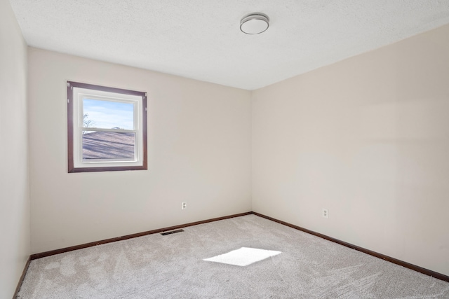 empty room featuring baseboards, visible vents, carpet floors, and a textured ceiling