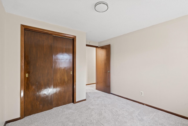 unfurnished bedroom with a closet, baseboards, and carpet