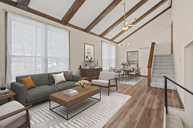 living room featuring stairway, wood finished floors, visible vents, high vaulted ceiling, and beamed ceiling