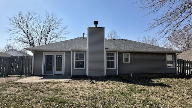 rear view of house with a yard, fence, roof with shingles, and a chimney